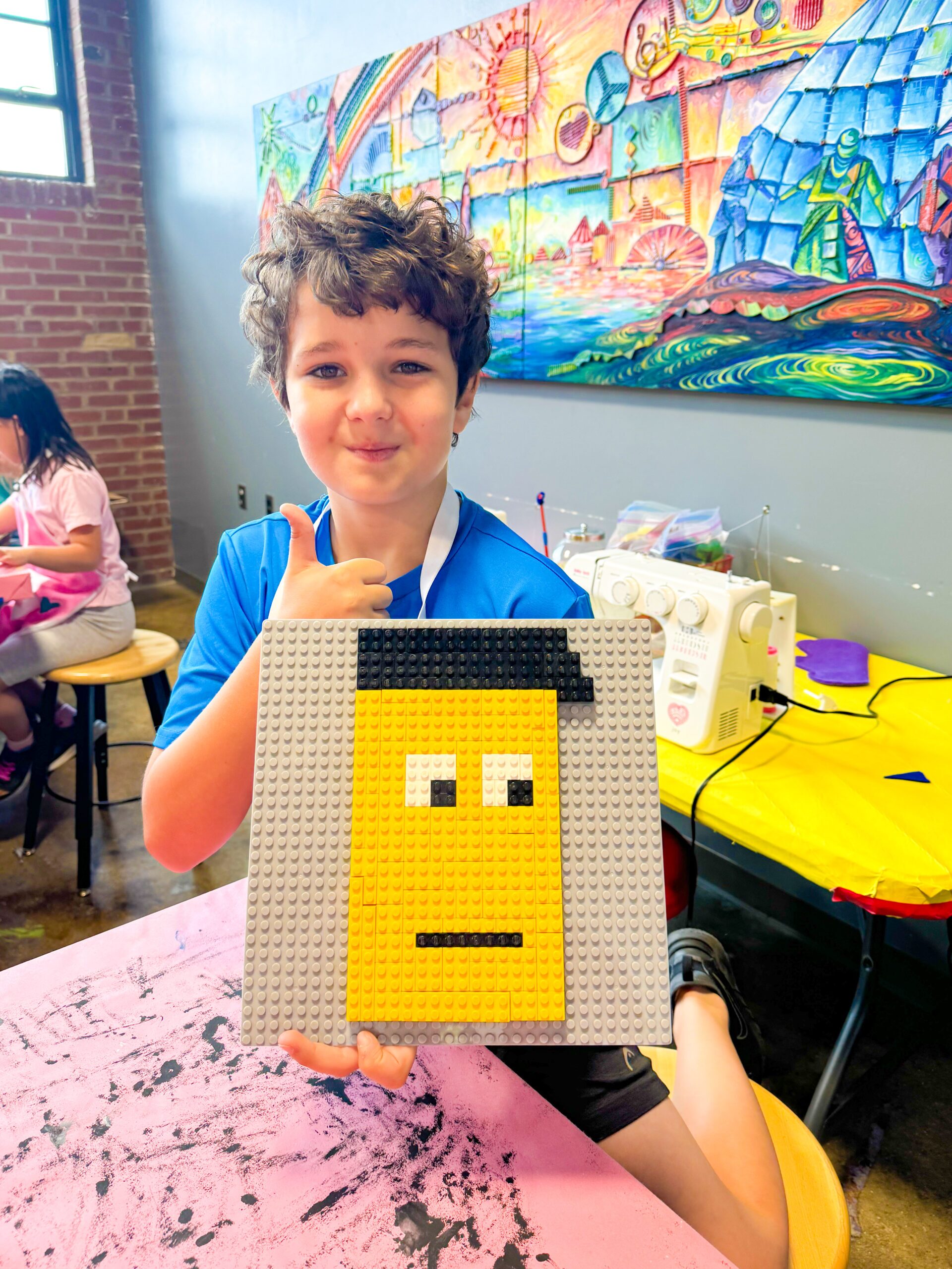 Child posing with craft at MADE for Kids summer camp