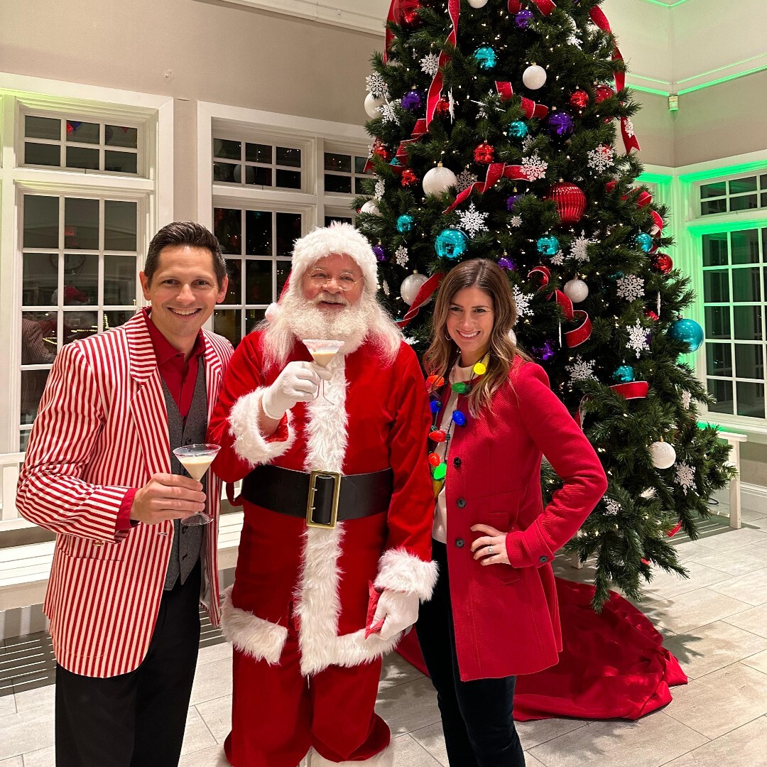 Couple posing in front of Christmas tree with Santa