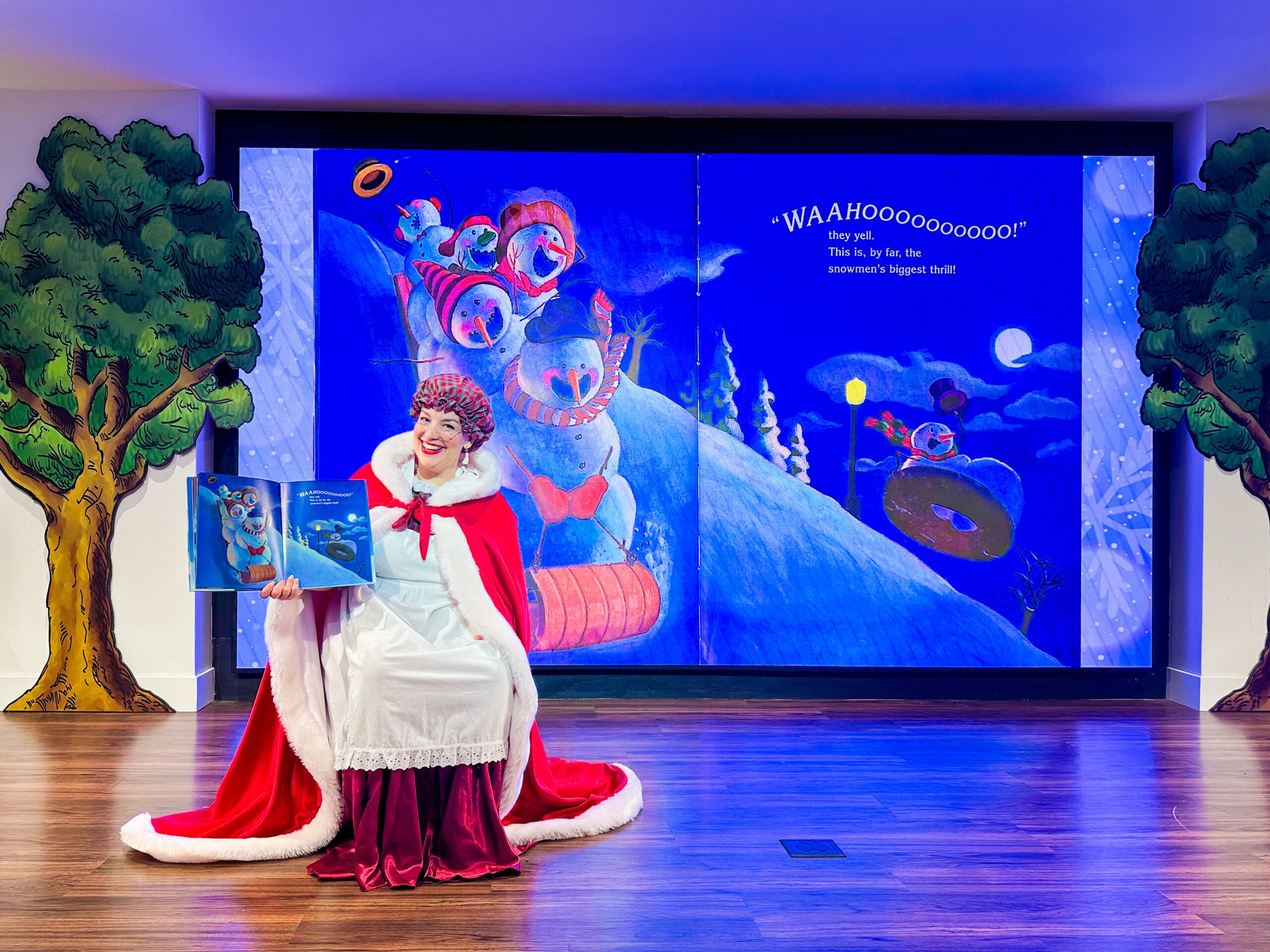 Mrs. Claus reading a story about snowmen on the stage of Story Time Theater