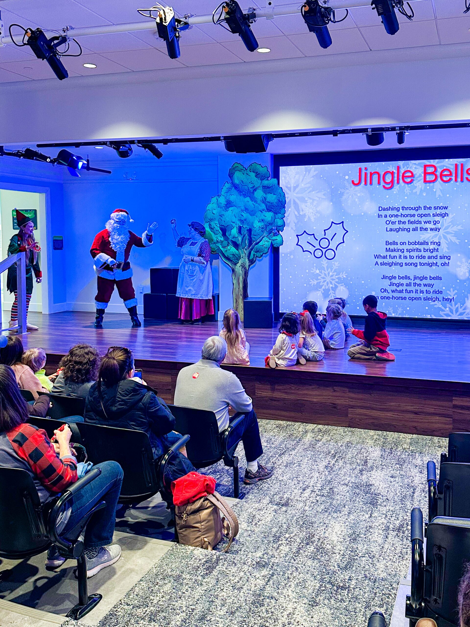 Mrs. Claus, Santa and elf sing Jingle Bells in Story Time Theater with kids