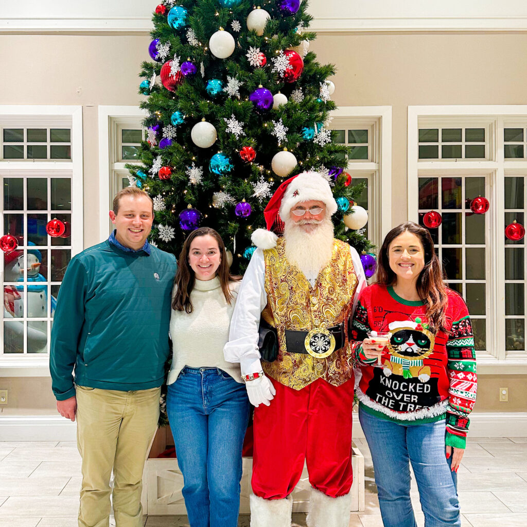 Young adults with Santa in front of Christmas tree at Adult Play Date Magic Holiday Pop-Up